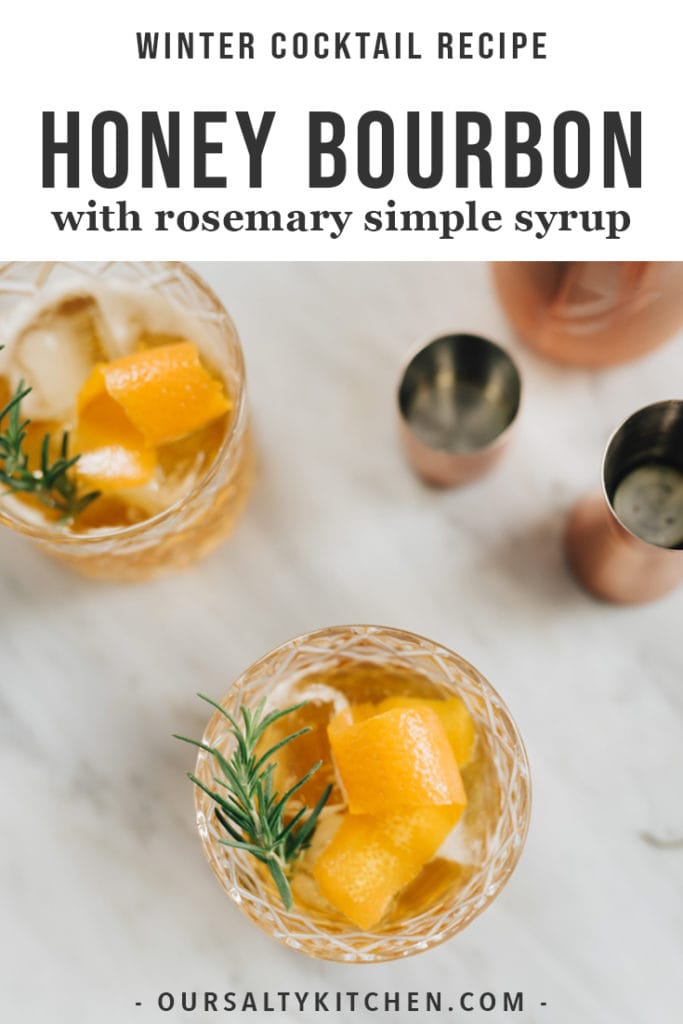 Two honey bourbon cocktails with rosemary simple syrup on a marble table with a bronze cocktail shaker.