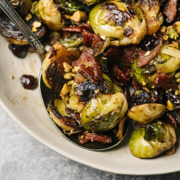 A vintage serving spoon tucked into a bowl of sautéed brussels sprouts with cranberries and pistachios.
