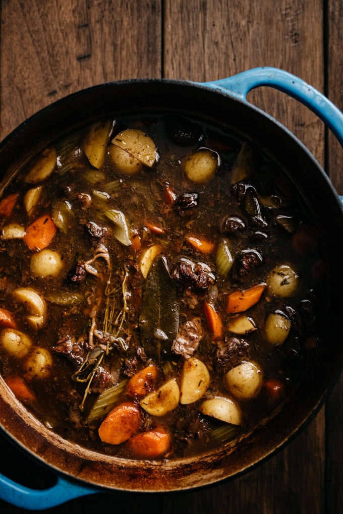 A large blue dutch oven filled with red wine beef stew fresh from the oven.