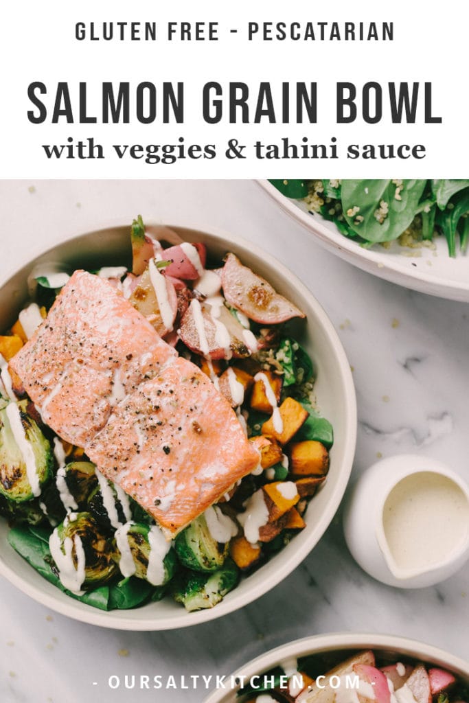 A bowl of quinoa tossed with fresh spinach, topped with roasted vegetables and pan seared salmon, drizzled with tahini dressing.