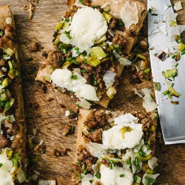 This savory focaccia recipe is an easy crowd pleaser. Layers of ricotta cheese, sweet italian sausage, and caramelized leeks baked atop dense, nutty focaccia bread. It's a super easy, filling, and fun party food.