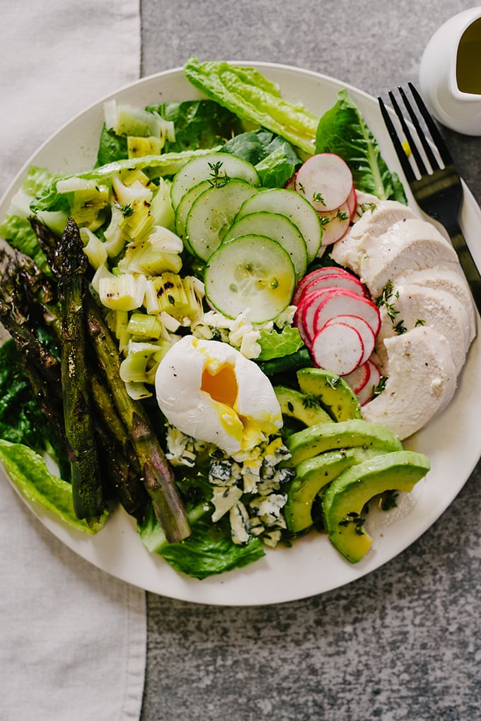 I love an easy salad recipe for weeknight dinners, especially one packed with protein and healthy fats! This spring cobb salad has a combination of grilled and raw vegetables with roasted chicken, avocado, blue cheese and a thyme red wine vinaigrette.