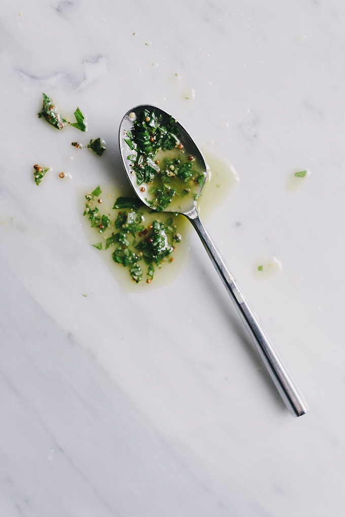 Basil dressing on a spoon for making a no mayo potato salad recipe.
