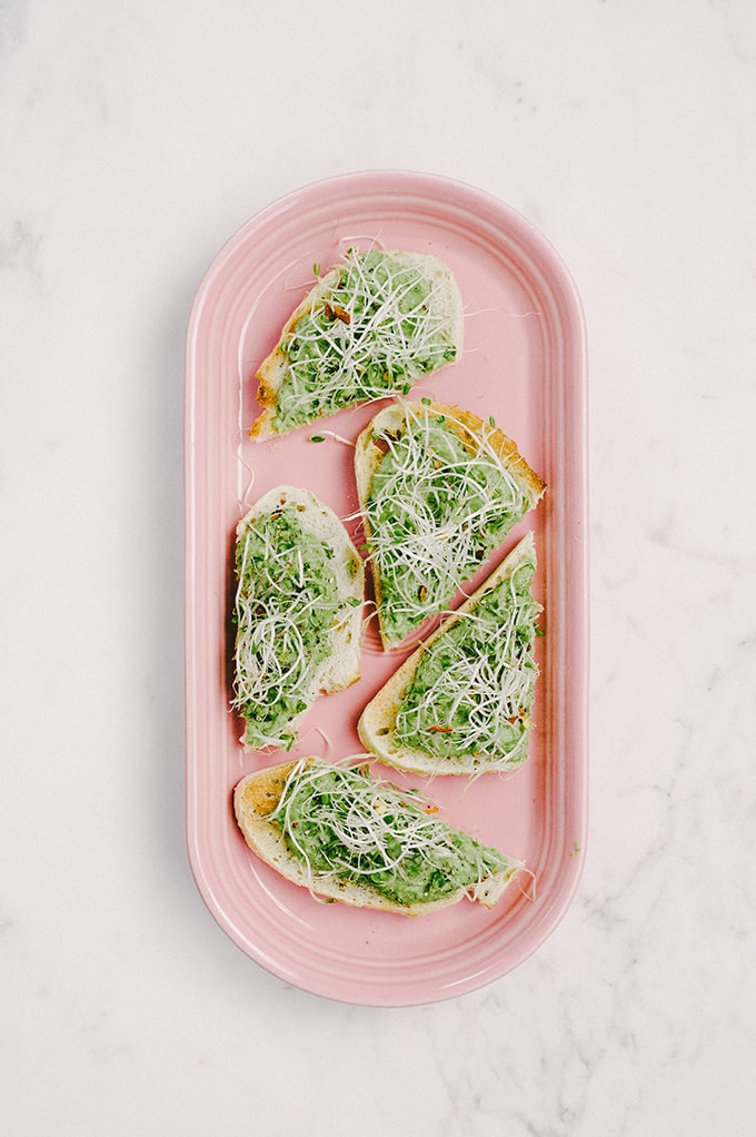 This roasted garlic sweet pea bruschetta is a sweet, seasonal spring recipe. It's great as an appetizer for a dinner party or served with a bit of extra protein and veggies for an open-faced sandwich.