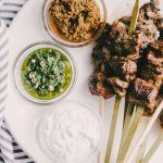 These paleo grilled flank steak skewers are a great party food recipe! Thin strips of grass fed flank steak is charred and crispy on the outside, and and tender on the inside. A real food dipping sauce trio of chimichurri, minty yogurt, and sundried tomato pesto keeps everyone happy. #healthy #wholefood #realfood #paleo #grassfed