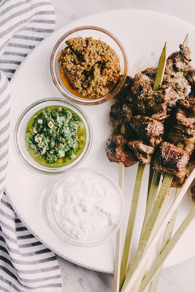 Grilled steak skewers are one of my favorite ways to feed a crowd. They are charred and crispy on the outside, and and tender on the inside. To keep everyone happy, I serve them with a dipping sauce trio of chimichurri, minty yogurt, and sundried tomato pesto.