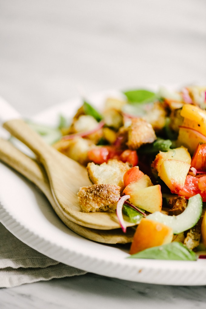 Peach panzanella is the best late summer whole food salad recipe. Juicy peaches and tomatoes, yeasty sourdough, fresh basil, and a champagne vinaigrette make summer produce shine. This is an easy recipe for a packed lunch or light dinner. #healthy #wholefood #realfood #eatclean #cleaneating