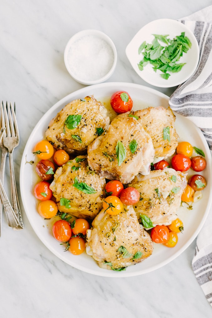 These crispy chicken thighs are whole foods family favorite. Crispy chicken skin, juicy thigh meat, and sweet tomatoes that burst with a satisfying little "pop". This is an easy, tasty, real food recipe that's on the table in just about 35 minutes. A winning weeknight dinner! #paleo #wholefood #realfood #whole30