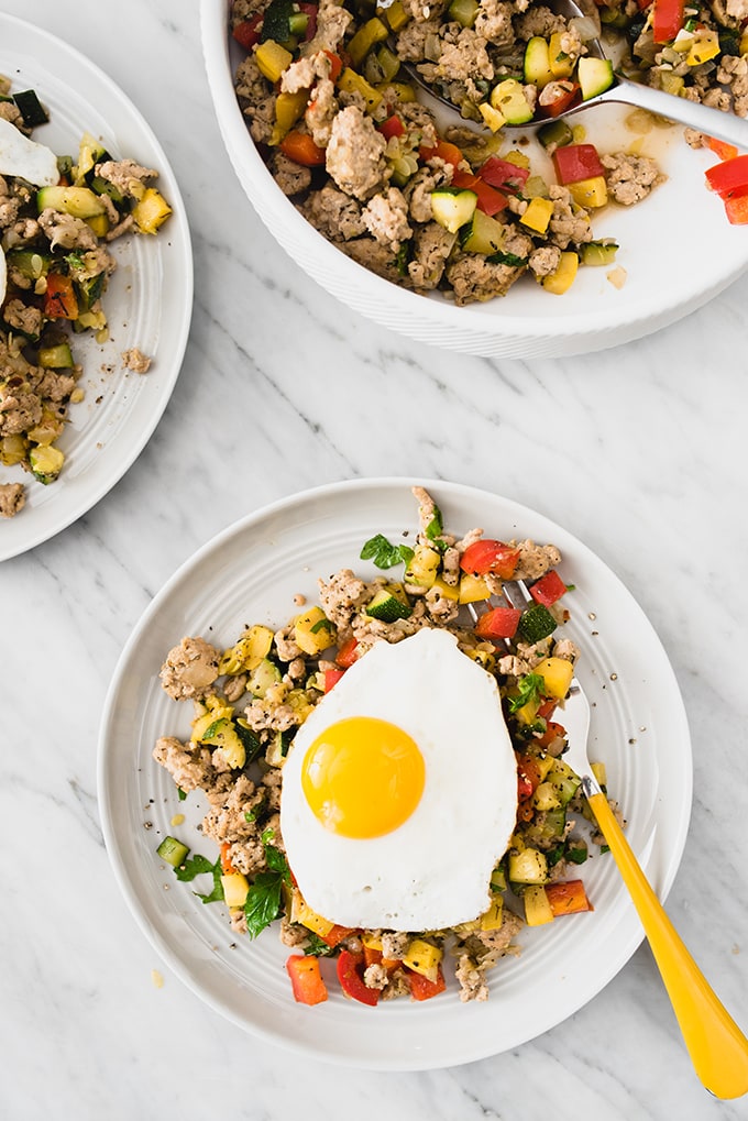 A fast and easy paleo ground turkey recipe. Ground turkey hash topped with a fried egg on a marble table. 