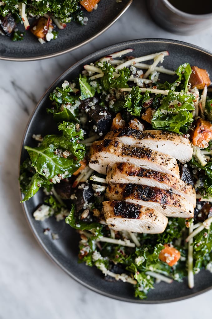 A plate of kale chicken salad, made with kale, apples, quinoa and roasted sweet and purple potatoes. 