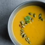 A bowl of roasted pumpkin soup. This healthy paleo soup is made with coconut milk, bone broth, and fall herbs and spices.