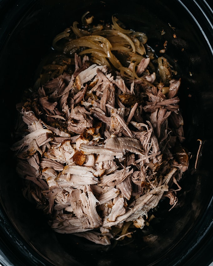 Cooked and shredded apple cider pulled pork in a slow cooker. 