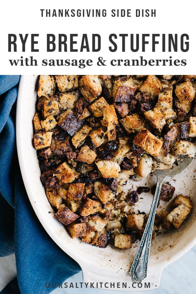 A casserole dish of sausage and cranberry stuffing with rye bread croutons with a blue linen napkin.