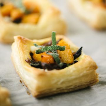 Baked mini butternut squash tart with ricotta cheese and caramelized onions on a baking sheet.