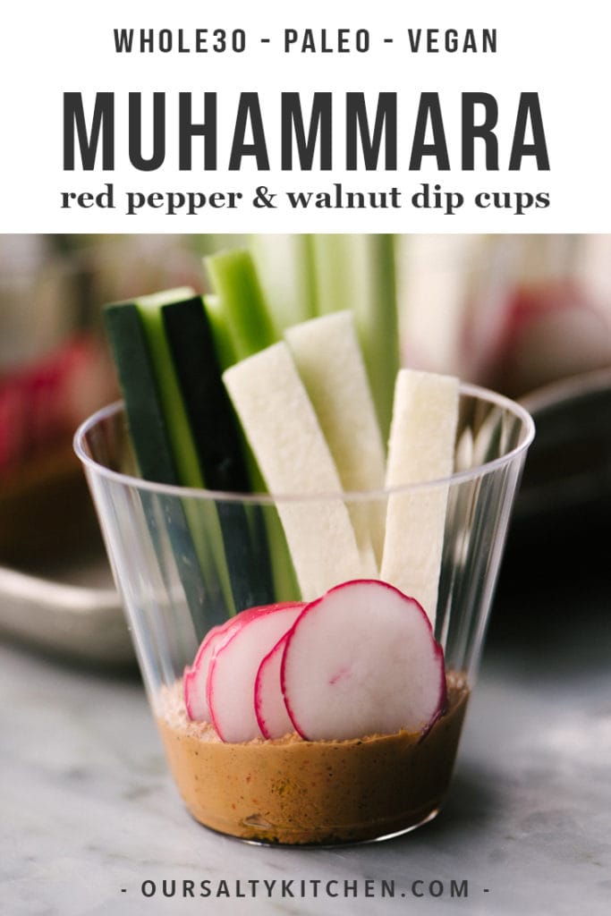 A plastic party cup filled with muhammara roasted red pepper spread and sliced vegetables.