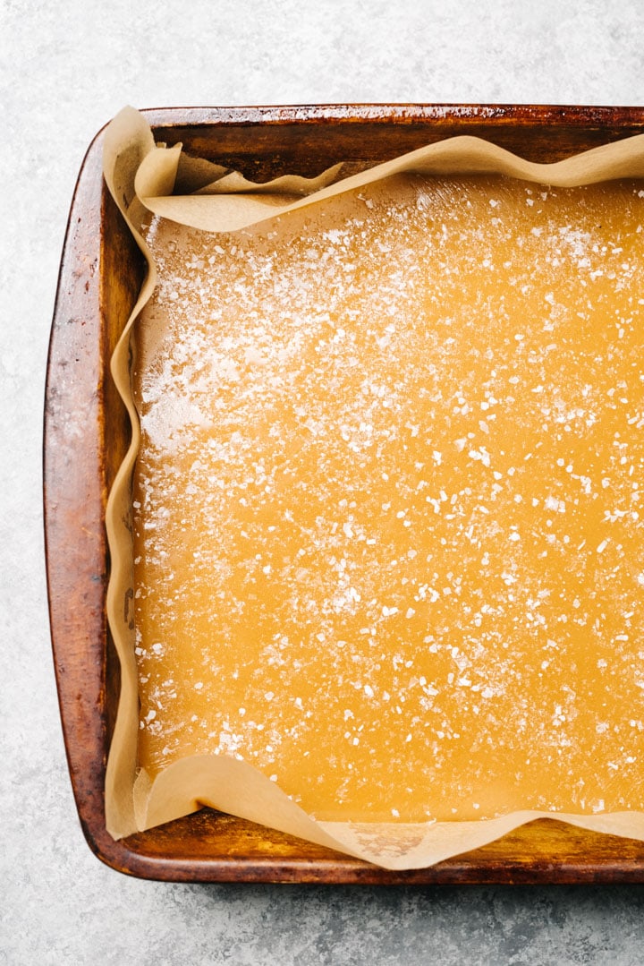 Caramel candy poured into a parchment lined casserole dish, sprinkled with sea salt.