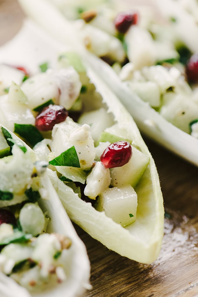 A detail image of an endive cup appetizer filled with pears, blue cheese, and pomegranate stuffing. 