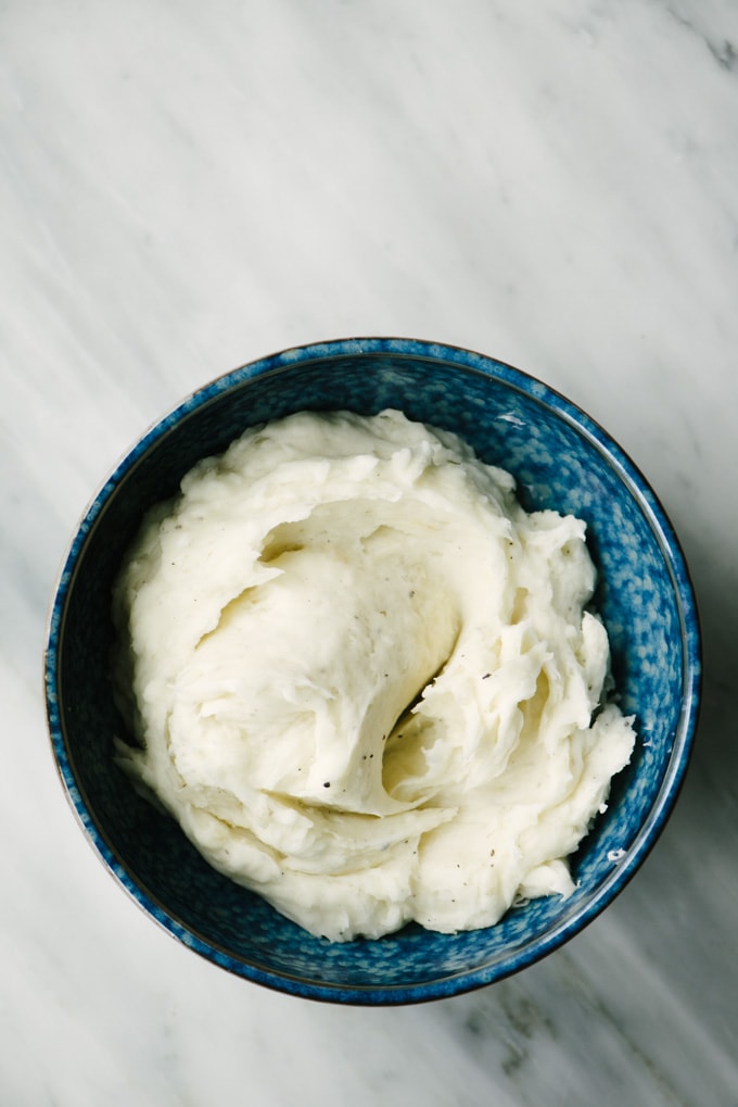 A blue bowl filled with creamy, garlic roasted yucca mash, my favorite yucca root recipe! 