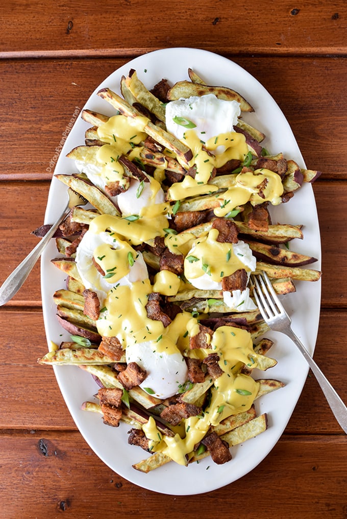 Whole30 pork belly breakfast benedict on a white platter with forks. 