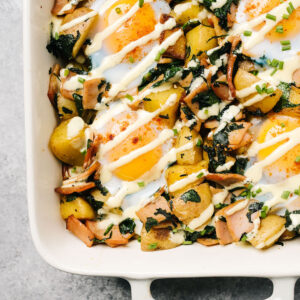 An eggs benedict casserole with runny eggs, drizzled with hollandaise sauce.