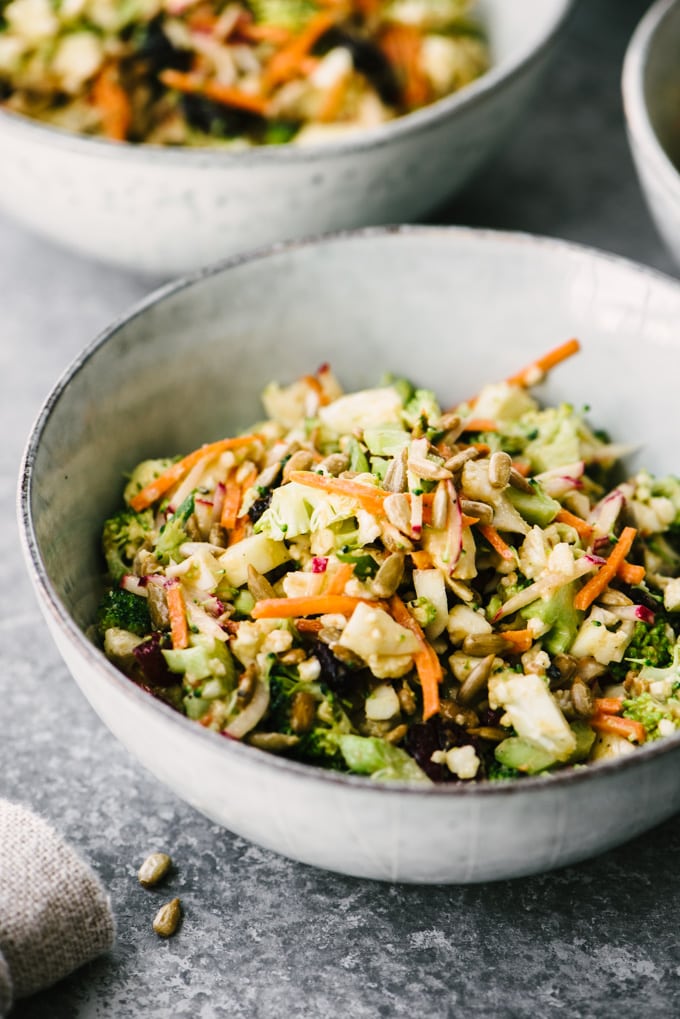 A ceramic bowl filled with paleo broccoli and cauliflower salad, the perfect summer paleo recipe for picnics and parties! 