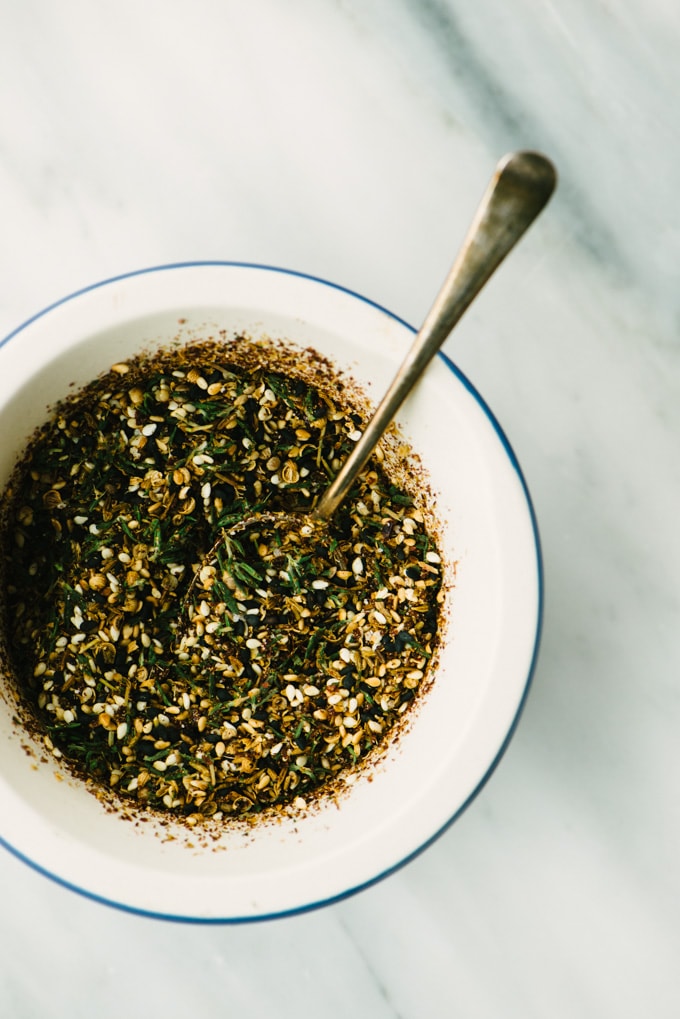 A bowl of homemade za'atar spice in a small bowl on a marble table. 