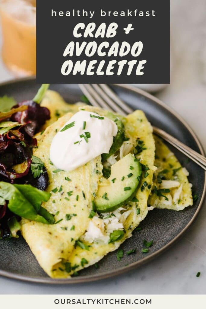 Side view, a fork tucked under a crab omelet on a grey plate with a tossed green salad; title bar at the top reads "healthy breakfast - crab and avocado omelette".