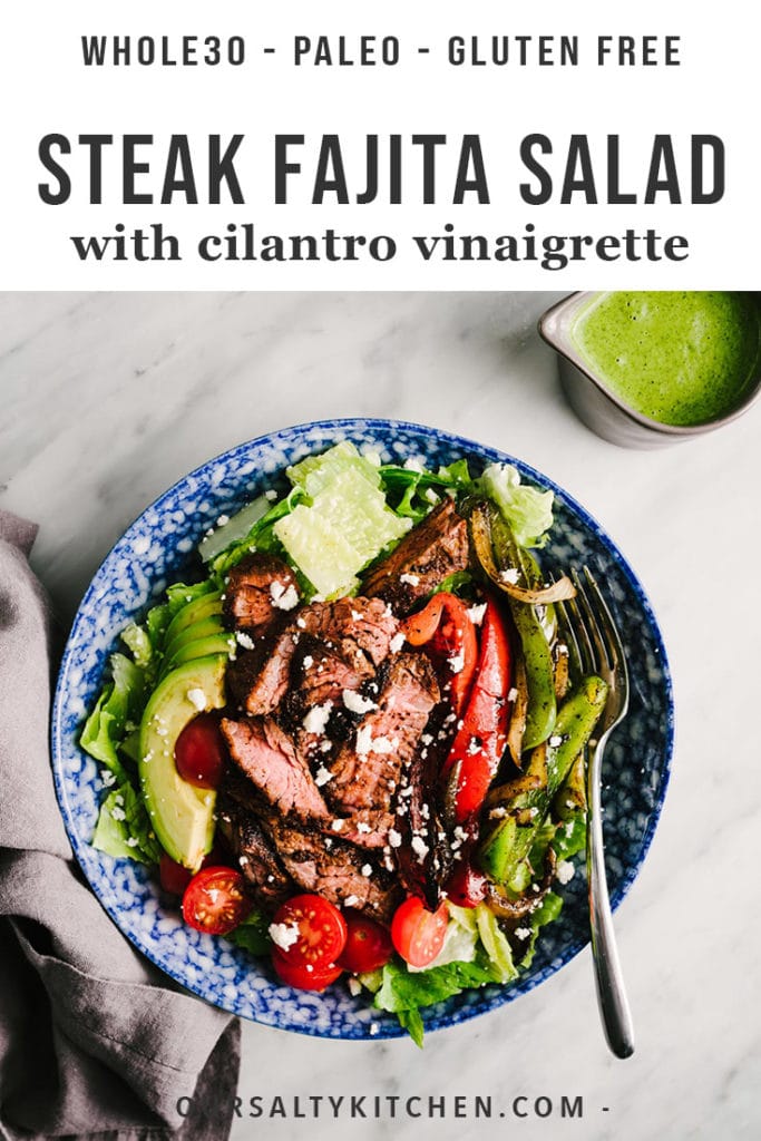A bowl of steak fajita salad with sautéed peppers and onions, avocado, and a side of cilantro vinaigrette.