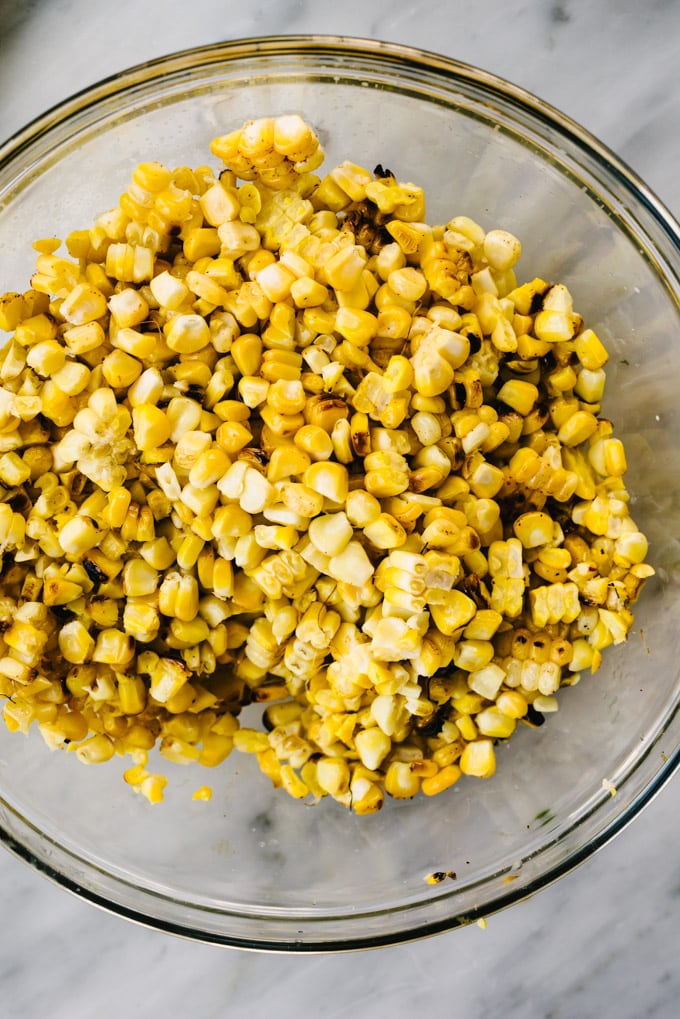 A bowl of fresh grilled corn kernels sliced from the cob on a marble table.