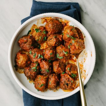 Paleo and whole30 turkey meatballs smothered with marinara sauce in a white serving bowl.