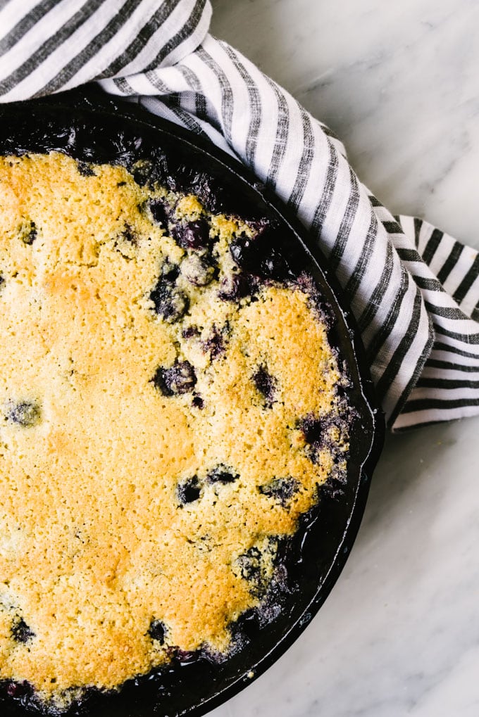 Blueberry cobbler in a cast iron skillet made with gluten free topping.