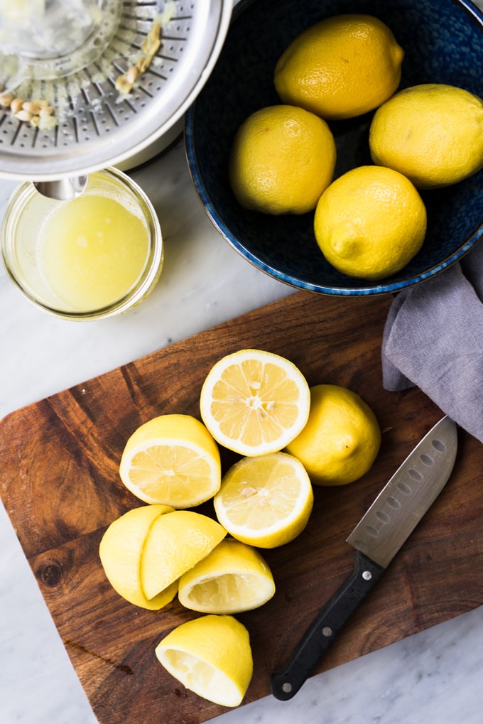 Lemons cut in half on a cutting board and juiced for fresh squeezed mint and basil lemonade.