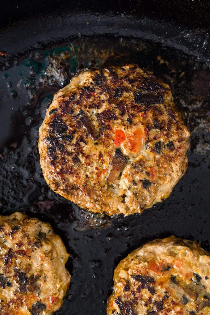 Paleo turkey burgers cooking in a cast iron skillet.