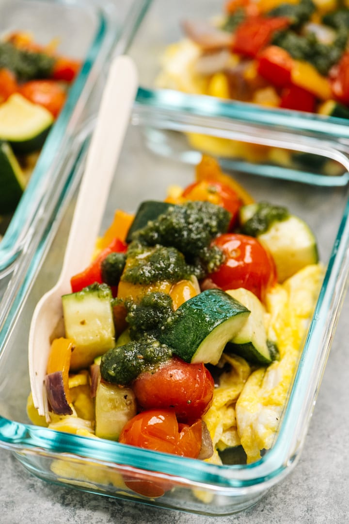 Scrambled eggs with roasted vegetables and dairy free pesto in a meal prep bowl.