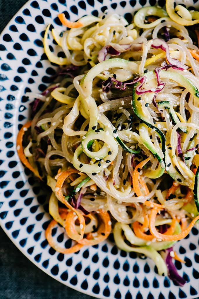 Paleo glass noodle salad with sweet potato glass noodles, zucchini and squash noodles, carrots, and red cabbage, dressed with sesame ginger vinaigrette.