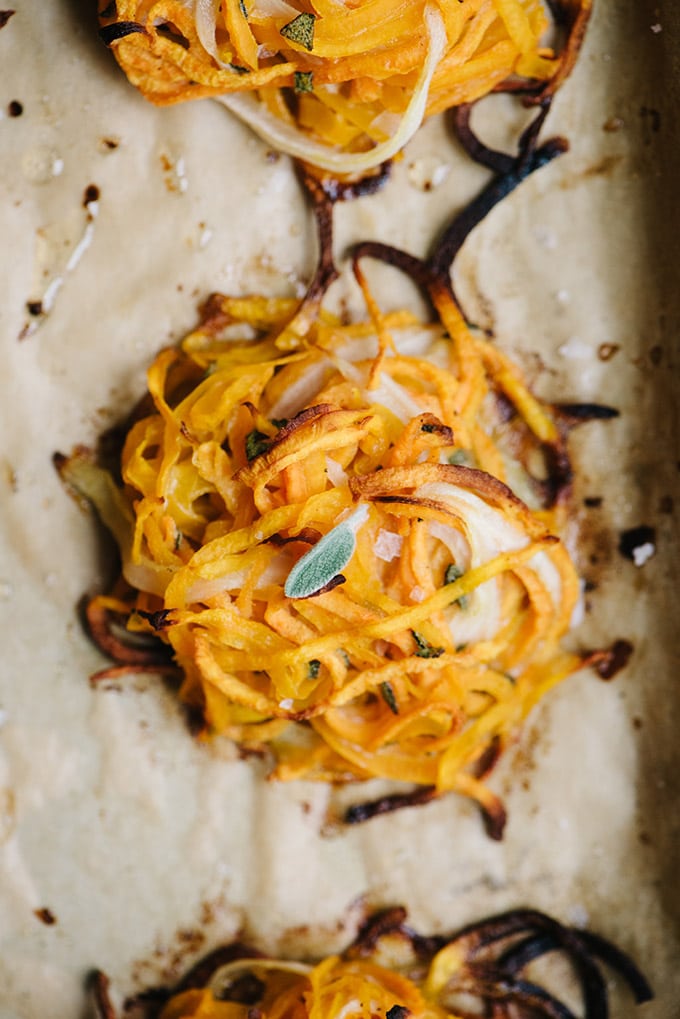 A butternut squash and sweet potato fritter garnished with fresh sage and flaky sea salt.