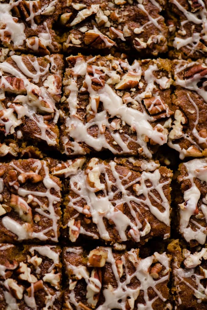 A tray of healthy pumpkin bars drizzled with vanilla glaze sliced into squares.
