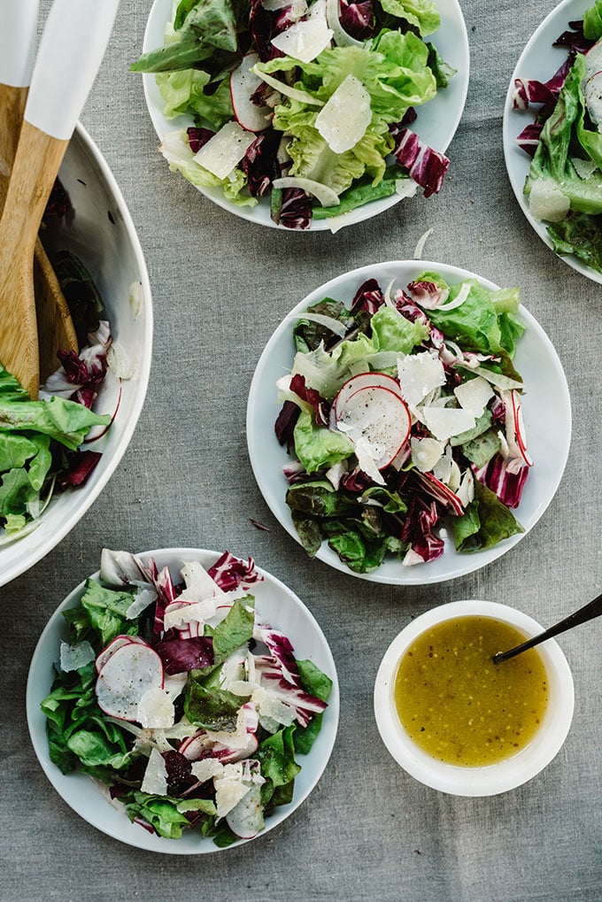 Several plates of butter lettuce salad with radicchio, fennel, radishes, and parmesan cheese with champagne vinaigrette.