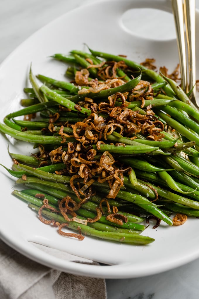 A dish of garlicky green beans topped with crispy shallots.