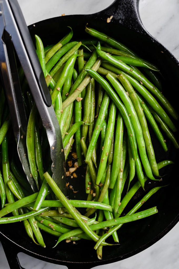 Green beans sautéed with garlic in a cast iron skillet.