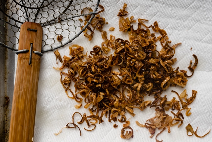 Fried crispy shallots draining on a paper towel.