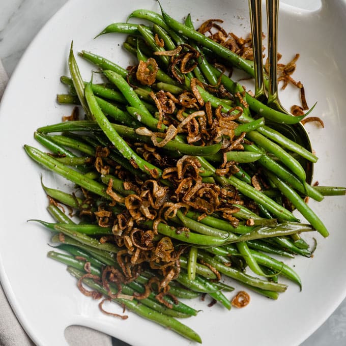Garlicky french green beans topped with crispy shallots in a serving bowl.