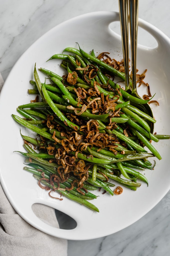 Garlicky french green beans topped with crispy shallots in a serving bowl.