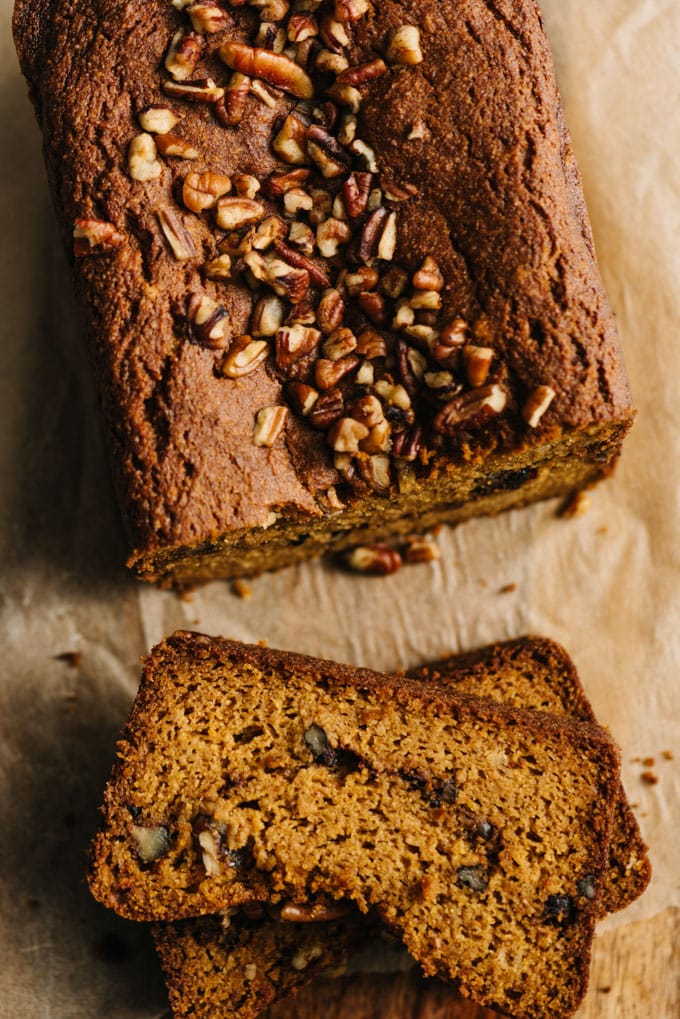A loaf of paleo pumpkin bread with two slices on a cutting board.