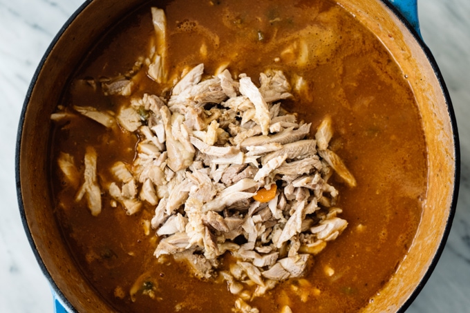 A simmering pot of pumpkin chili with shredded chicken added on top.