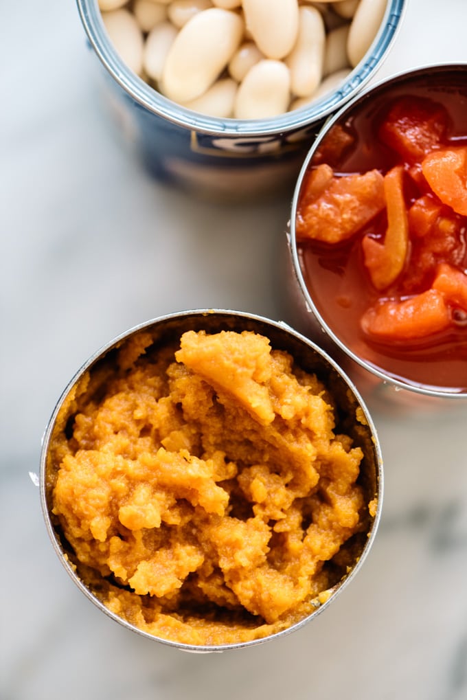 Three open cans of pumpkin puree, diced tomatoes, and white beans.