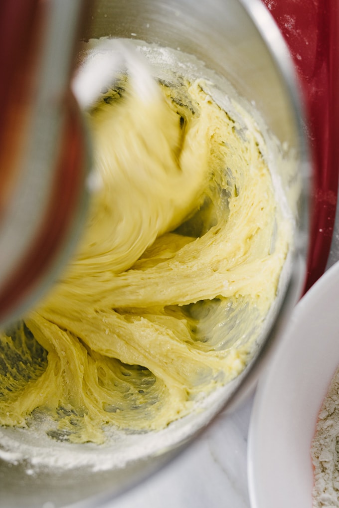 An overhead view of chrusciki dough being mixed in an electric mixer.