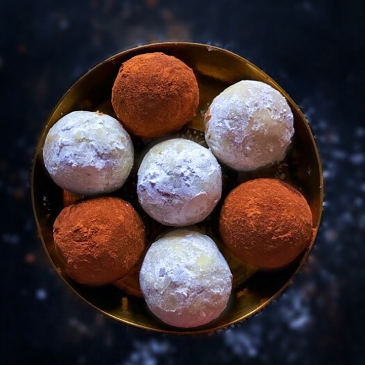 Gingerbread cookie truffles in a gold bowl on a chalkboard background.