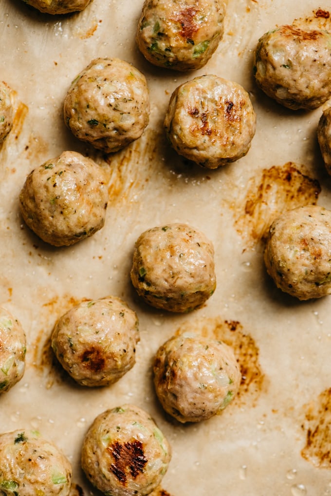 Turkey meatballs seasoned with sage and thyme on a baking sheet.