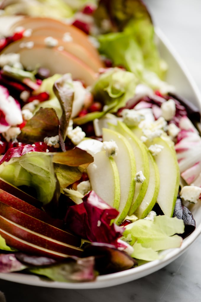 A close up image of a platter of winter chopped salad with pear, endive, and pomegranate.